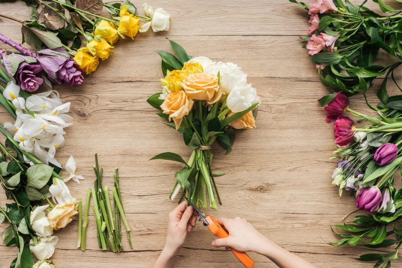 cropped-view-of-florist-cutting-flower-stalks-in-bouquet-on-wooden-surface.jpg